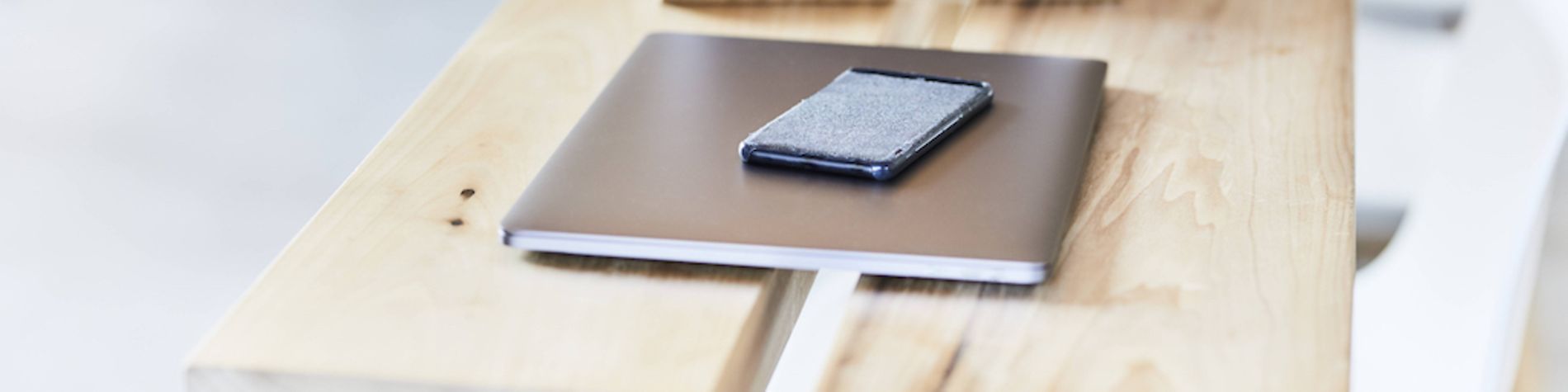 Tablet, Smartphone und Laptop liegen auf einem Tisch.